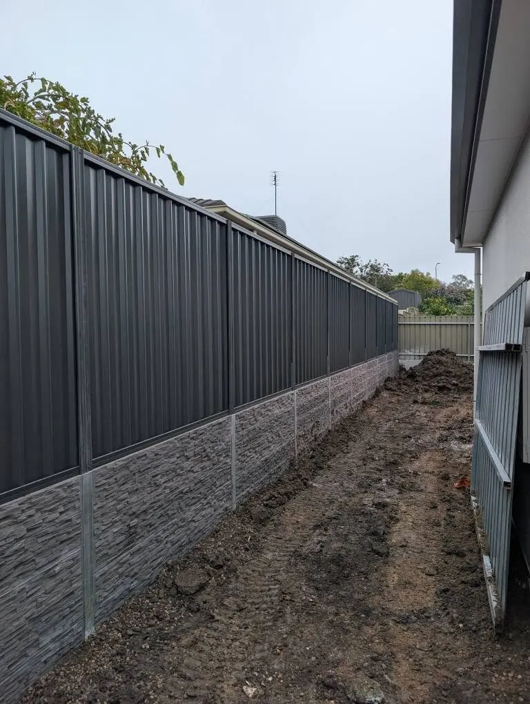 Stone look concrete sleeper retaining wall with Colorbond fence on top