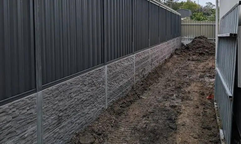 Stone look concrete sleeper retaining wall with Colorbond fence on top