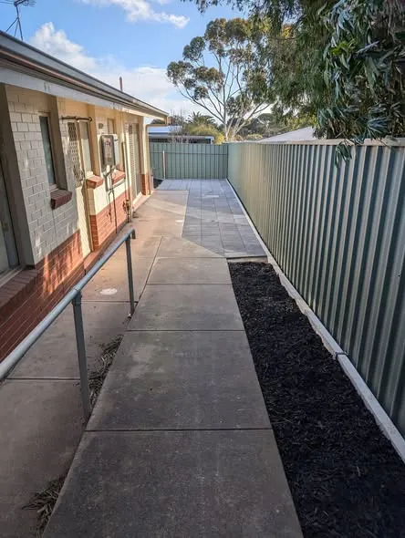 Side yard with new paving and a mulched garden bed along a Colorbond fence